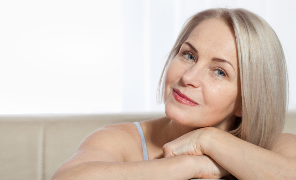 Woman with mature skin resting her chin on her hand, representing collagen changes and skin firmness with age.